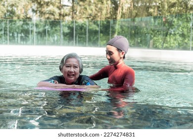 Young trainer helping senior woman in aqua aerobics and working out in the pool. old woman and mature man doing aqua aerobics exercise in swimming pool, Elderly sports, and active lifestyle concept. - Powered by Shutterstock