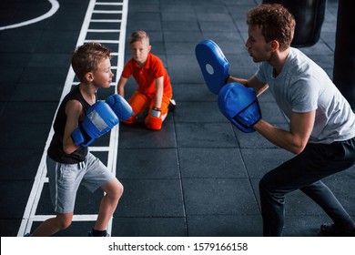 Young Trainer Teaches Kids Boxing Sport In The Gym.