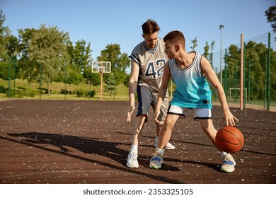 Young trainer teaching teenage boy playing basketball on street court - Powered by Shutterstock