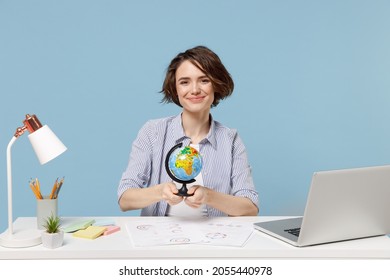 Young Travel Agent Successful Secretary Employee Business Woman In Casual Shirt Sit Work At White Office Desk With Pc Laptop Hold Earth World Globe Isolated On Pastel Blue Background Studio Portrait.