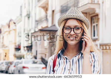 Young travel girl talking on phone. Woman on summer style cloth and hat on transparent glasses. People and technology concept 