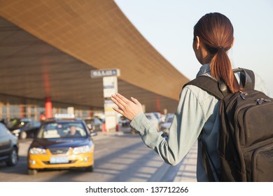 Young Traveler Hailing A Taxi At Airport