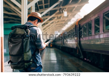 Young traveler on railroad station using phone in train station,copy space.