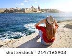 Young traveler woman holds hat looking at Valletta old town travel destination in Malta