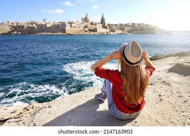 Young traveler woman holds hat looking at Valletta old town travel destination in Malta