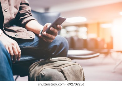 Young Travelers Living Smartphones Waiting For Mass Transit System Waiting For The Plane To Go On Vacation On Weekend Over Blurred Terminal. Select Focus And Film Tone With Light Fair