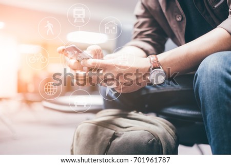 Young travelers Use smartphone to find travel information from the application. waiting for mass transit system go vacation on weekend over blurred Terminal. select focus and Film Tone with Light fair