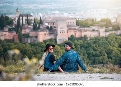 A young traveling couple on their honeymoon contemplate the views of the Alhambra palace in the city of Granada, Spain