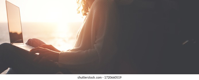 Young traveling female sitting in the trunk of van and enjoing the adventure, woman hipster using laptop in the car at sunset. Wide screen, panoramic - Powered by Shutterstock