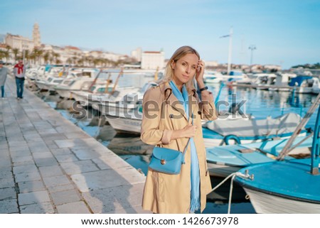 Young traveling woman in coat  walking on Split promenade sea embankment enjoying the view.