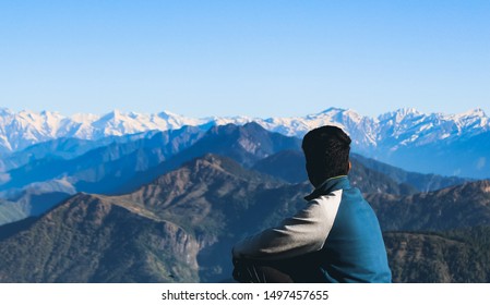 Young traveller looking at snowcapped mountain peaks and vast mountain ranges, freedom and grand life concept, solo travel