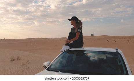 Young Traveller Woman Sitting On The Car In Desert. Travel Concept.