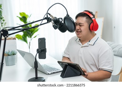 Young Trendy DJ Man Wearing Headphone And Speak On Microphone At Studio. Teenager Patient Person Feeling Happy And Relax While Recording News Sound Podcast Show For Radio Broadcasting At Home Studio.