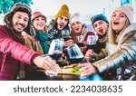 Young trendy friends toasting red wine at restaurant garden out side - Life style concept with mixed happy people having fun together at winery bar eatery wearing winter clothes - Viva magenta filter