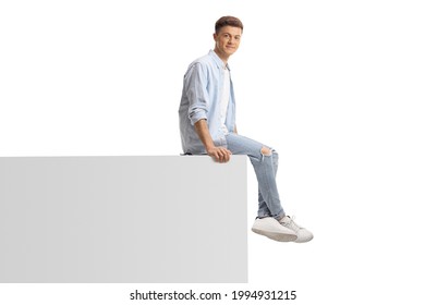 Young Trendy Man Sitting On A White Wall Isolated On White Background