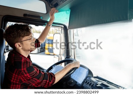 Young truck driver activating tachometer , sitting in truck cabin , ready to go 
