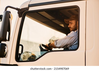 Young Truck Driver Looking At Side View Mirror While Driving In Reverse.