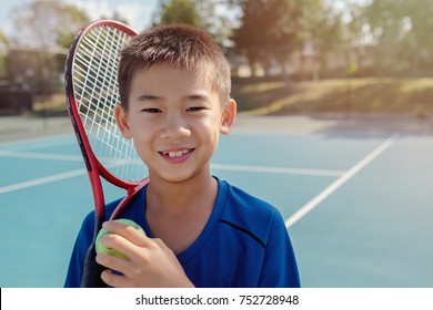 Young tween preteen mixed Asian boy tennis beginner player on outdoor blue court