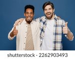 Young two friends happy fun cool men 20s wear white casual shirts together looking camera put hand on shoulder show thumb up isolated plain dark royal navy blue background. People lifestyle concept