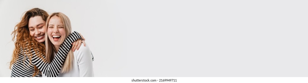 Young Two Women Laughing While Making Fun Together On Camera Isolated Over White Background