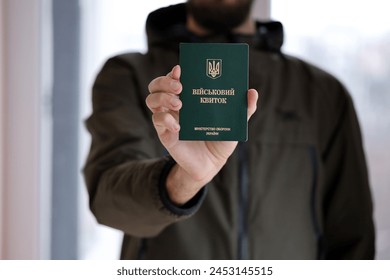 Young ukrainian conscript soldier shows his military token or army ID ticket indoors close up - Powered by Shutterstock