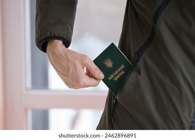 Young ukrainian conscript soldier shows his military token or army ID ticket indoors close up - Powered by Shutterstock