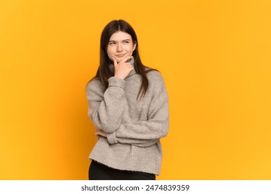 Young Ukrainian girl isolated on yellow background thinking an idea while looking up