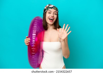 Young Ukrainian woman holding air mattress isolated on blue background counting five with fingers