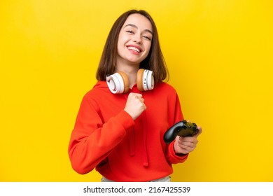 Young Ukrainian woman playing with a video game controller isolated on yellow background celebrating a victory