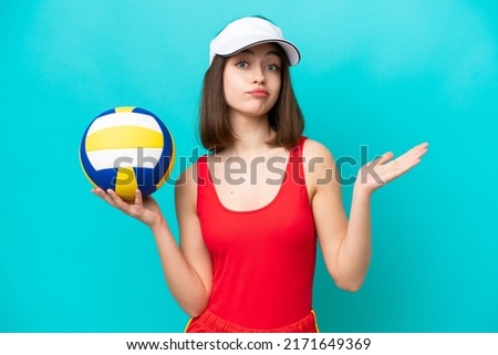 Young Ukrainian woman playing volleyball on a beach isolated on blue background having doubts while raising hands