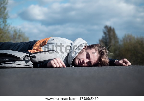 Young unconscious dead man at accident scene,\
crash on the road. Pedestrian guy, teenager hit by a car on the\
road while crossing highway. Downed male person is lying on\
asphalt. Dangerous\
situation