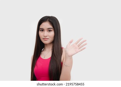 A young uneasy asian woman waving someone off expressing disinterest or apprehensiveness. Isolated on a white backdrop. - Shutterstock ID 2195758455