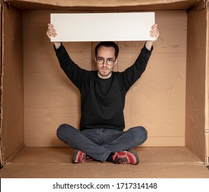 young unemployed man holding a white board, a place for advertising, the idea of a cry for help