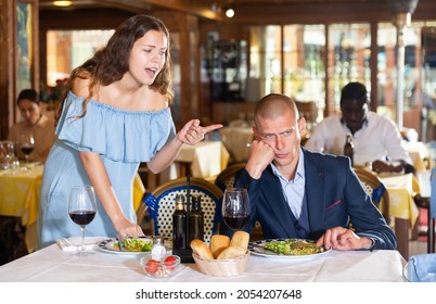 Young Unhappy Couple Quarreling During Dinner At Restaurant