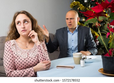 Young Unhappy Couple Quarreling At Room Decorated For Christmas Celebration