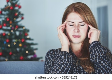 Young Unhappy Girl Has Headache Of Christmas Stress With Tree In Background