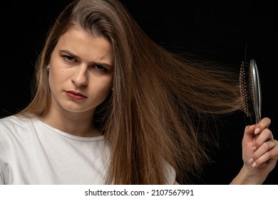 Young Unhappy Woman With A Hair Brush And Static Electric Hair Stand On Ends, On Black Background.