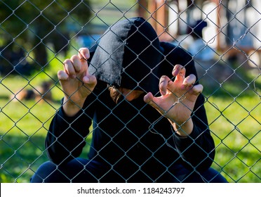 Young Unidentifiable Teenage Boy Holding The Wired Garden At The Correctional Institute , Conceptual Image Of Juvenile Delinquency, Focus On The Boys Hand.