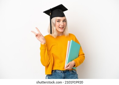 Young university caucasian woman graduate isolated on white background smiling and showing victory sign