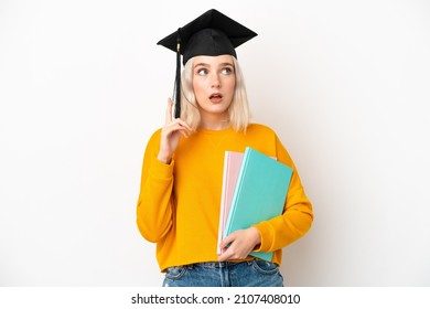 Young university caucasian woman graduate isolated on white background thinking an idea pointing the finger up
