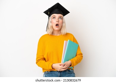 Young university caucasian woman graduate isolated on white background looking up and with surprised expression