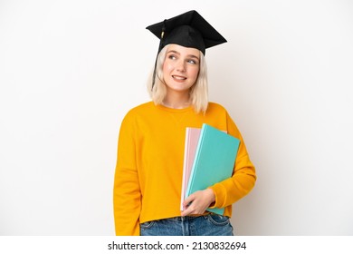 Young university caucasian woman graduate isolated on white background thinking an idea while looking up