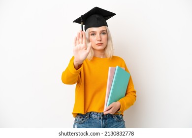 Young university caucasian woman graduate isolated on white background making stop gesture