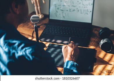 Young University Professor Is Doing Online Lecture For His Students From Home During Lockdown. He Is Using Laptop And Graphic Tablet And Is Writing Math Formulas With Stylus Pen