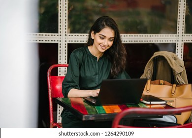 A Young University Student (Indian Asian Woman) Is Studying And Working On Her Laptop Computer At A Table During The Day. She Is Attractive And Beautiful.