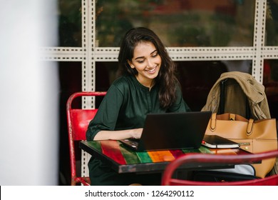 A Young University Student (Indian Asian Woman) Is Studying And Working On Her Laptop Computer At A Table During The Day. She Is Attractive And Beautiful.