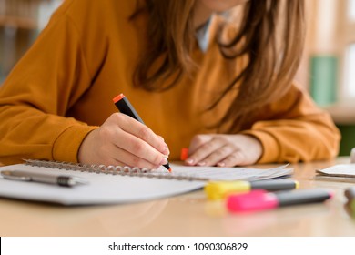Young unrecognisable female college student in class, taking notes and using highlighter. Focused student in classroom. Authentic Education concept. - Shutterstock ID 1090306829