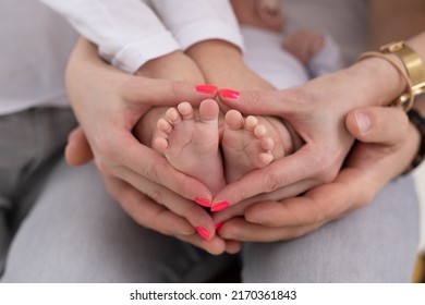 Young Unrecognizable Family Of Mother Father And Child. Mom, Dad And Kid Hold Legs, Foot Of Newborn Baby 