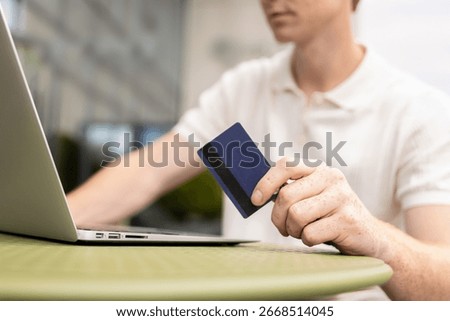 Young unrecognizable man checking payment page entering card number confirming transaction