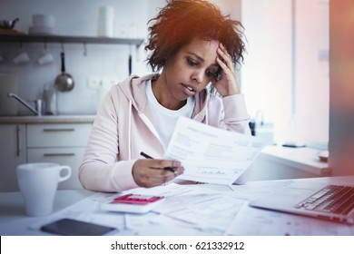 Young Upset African American Female Sitting At Kitchen Table With Laptop, Dealing With Financial Stress, Feeling Pressure Because Of Mortgage Debt, Worrying A Lot Or Feeling Anxious Over Money